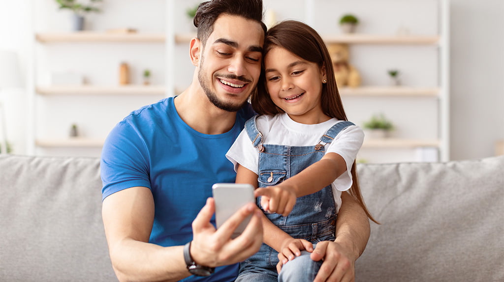 Criança e seu pai acessando aplicativos no celular